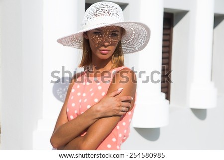 Young beautiful woman in hat with shadows on the face posing in white house