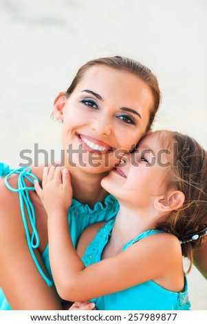 Happy family mother and girl resting on the beach in beautiful turquoise azur dresses