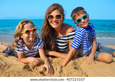 Happy family mother, daughter and son having fun on beach sand. Parent mom and children kids with toys at sea. Summer vacation holidays relax and happiness.