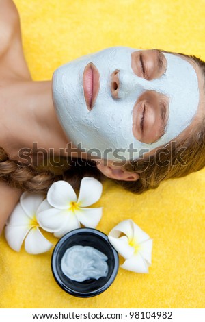 Beautiful happy woman in a tropical spa making face mask treatment
