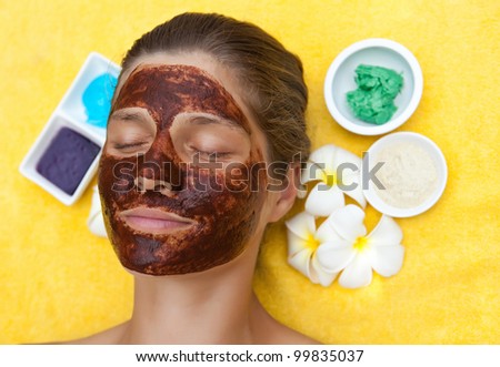 Beautiful woman in tropical spa making face mask and other treatments