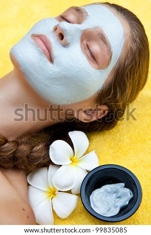Beautiful woman in tropical spa making face mask and other treatments