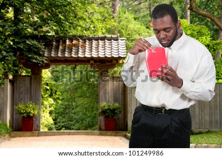 Black African American man eating Chinese or Japanese Asian food