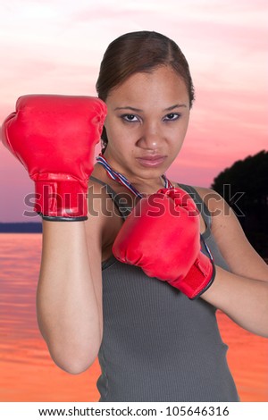Beautiful young black African American woman wearing a pair of boxing gloves