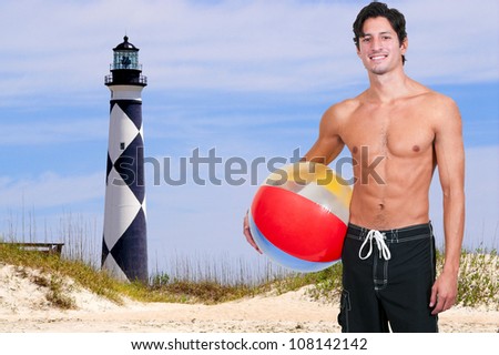 Young man holding a beach ball at the ocean
