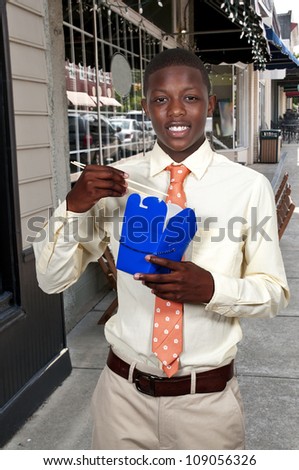 Handsome teenage black African American man eating Chinese Japanese or Asian takeout food