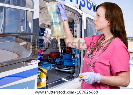 Beautiful young woman doctor holding an IV bag in front of a life flight helicopter