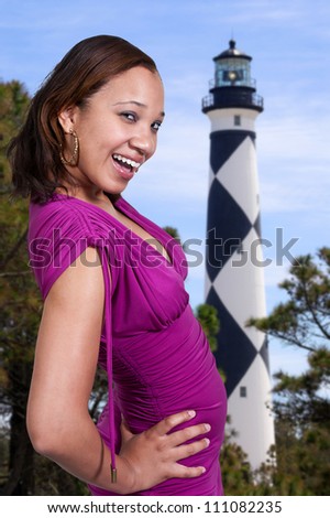 A beautiful young black African American woman tourist on vacation at a historical lighthouse
