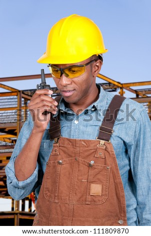 Handsome black man construction worker talking on a walkie talkie