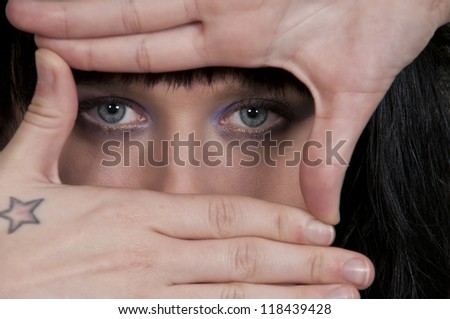 Beautiful young vulnerable scared or surprised woman looking through her hands