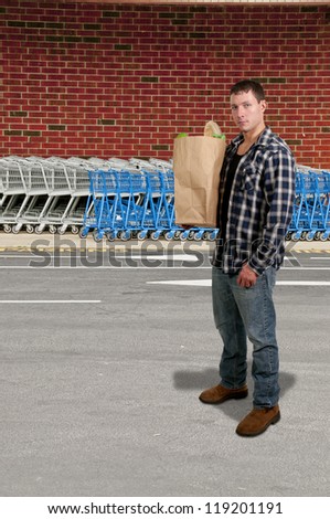 Handsome man grocery shopping holding a brown paper bag