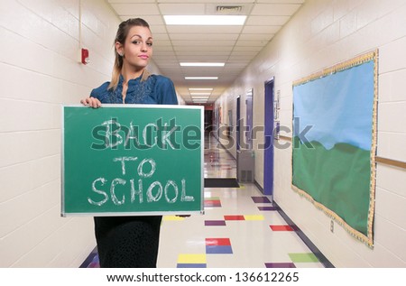 Woman holding a chalkboard that says back to school