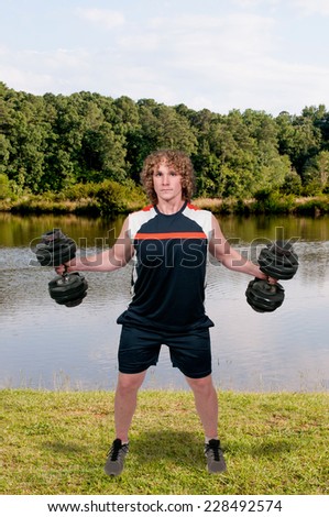 Handsome young muscular man lifting a weight