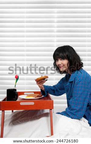 Beautiful woman eating a big breakfast in bed