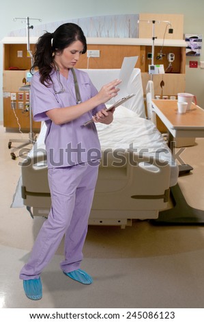 Beautiful young woman doctor in scrubs holding a patient record
