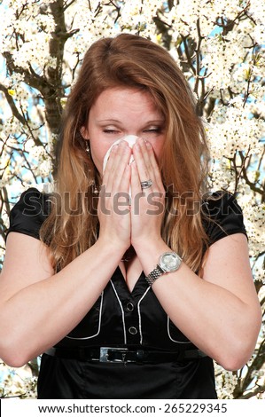 Beautiful woman with a cold, hay fever or allergies blowing her nose