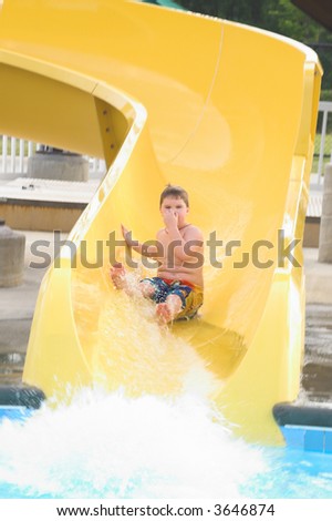 A young boy sliding down a water slide.