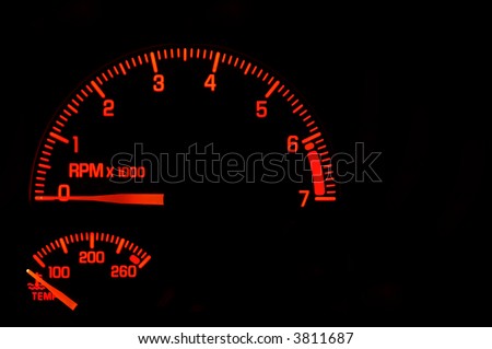 A red tachometer and temperature gauge on an automobile dashboard.