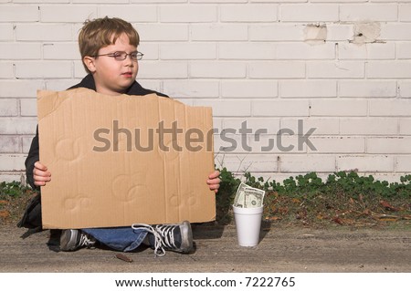 A homeless boy with a blank cardboard sign.