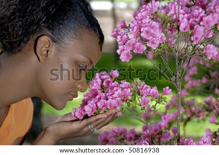 A young black woman stopping to smell the flowers