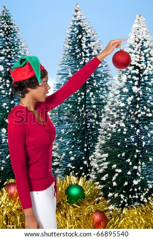 A beautiful young black woman holding or hanging a Christmas ornament