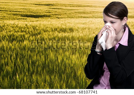 A beautiful woman with a cold, hay fever or allergies blowing her nose