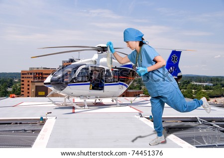 A beautiful young female doctor holding an IV bag in front of a medical ambulance helicopter