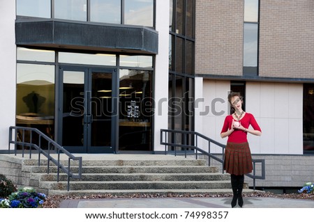A beautiful woman standing in front of a bank while holding a piggy bank full of money she has saved