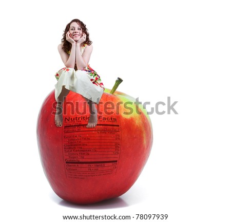 A beautiful young woman sitting on a whole red delicious apple with a nutrition label