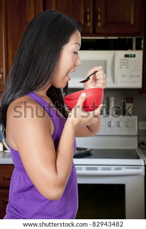 A beautiful Asian woman eating food from a bowl