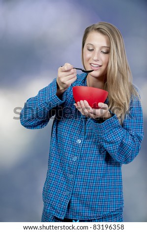 A beautiful woman wearing pajamas eating food from a bowl