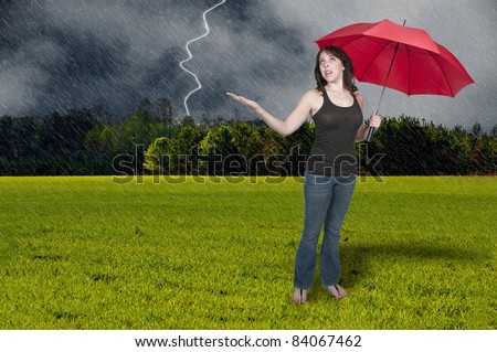 A beautiful young woman holding an umbrella in a rain and lightning thunderstorm