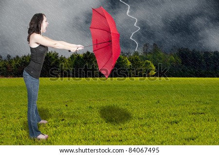 A beautiful young woman holding an umbrella in a rain and lightning thunderstorm