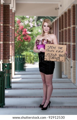 A beautiful young woman holding up a sign