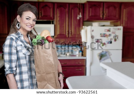 A beautiful woman grocery shopping holding a brown paper bag