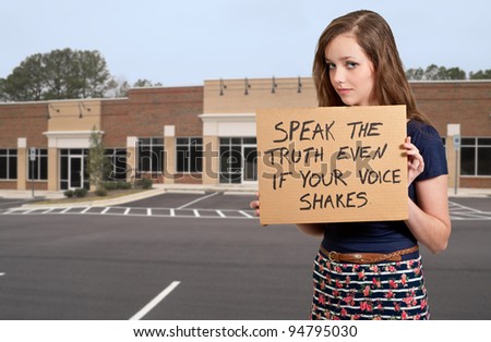 A beautiful young teenage woman holding up a sign