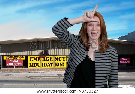 A woman giving the loser sign standing outside a store going out of business
