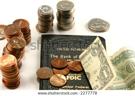dollar bill and stacks of coins around bank deposit book