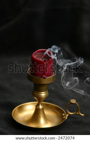 Extinguished candle with unique smoke pattern to the side over dark background
