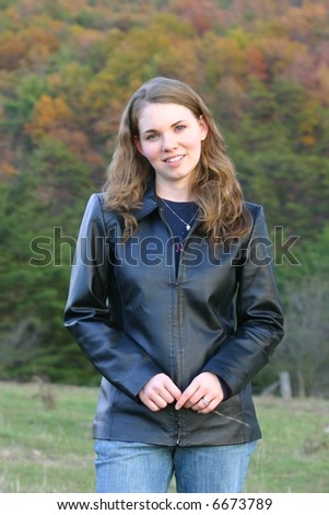 Pretty lady in black leather jacket against a fall background