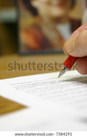 Teacher grading test paper at desk with red pen