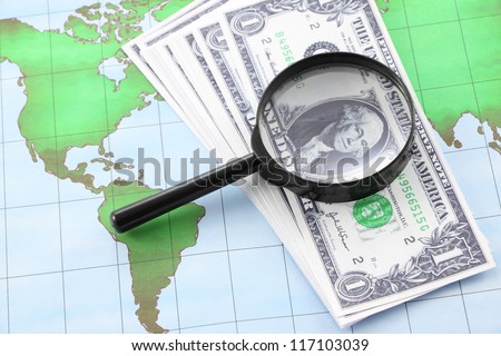 Magnifying glass black frame and currency on world map paper.