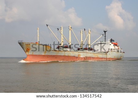 Old industrial product ship float on wide river.