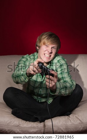 young man playing video games on red background