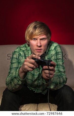 Young man playing video games on red background