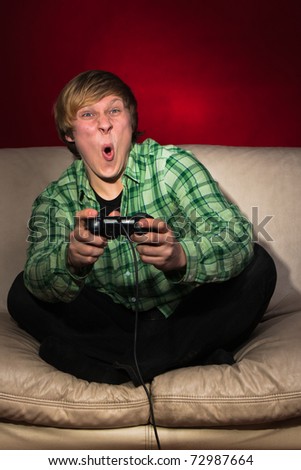 Young man playing video games on red background