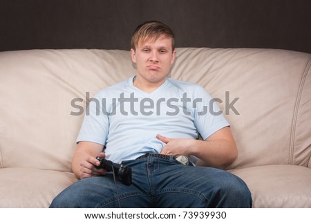 young man looks weird while playing video games on gray background