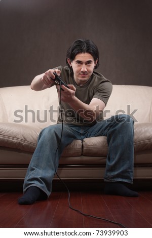 portrait of a young man playing video games on gray background