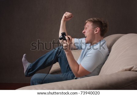 profile portrait of an excited young man playing video games on a gray background