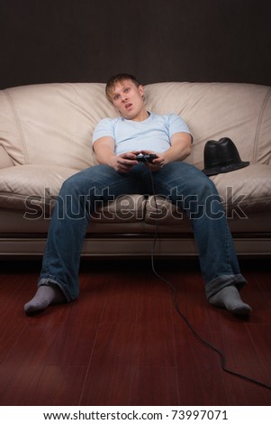 Young man playing video games on gray background